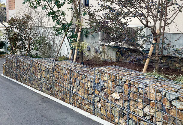 メッシュ状の格子パネルを組み上げ、その中に自然石を詰めるゴテの施行画像